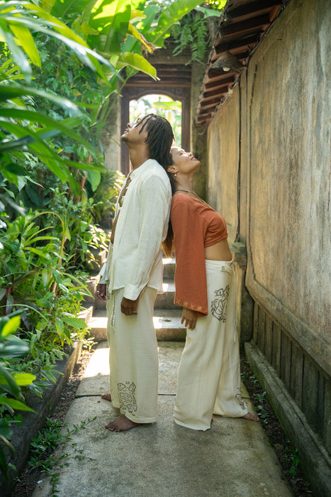 Two people standing close together in a garden setting with lush greenery.