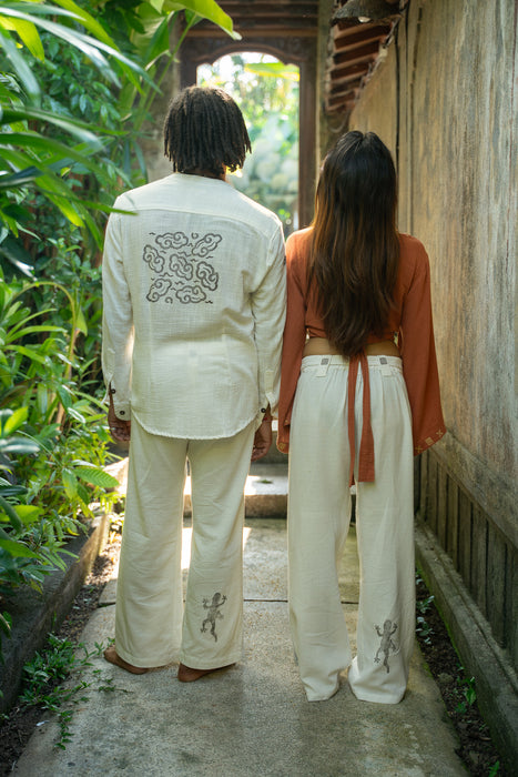 Two people standing together outdoors, wearing matching outfits with embroidered designs.