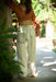 Person wearing a brown top and white pants with patterns, standing in a tropical setting.
