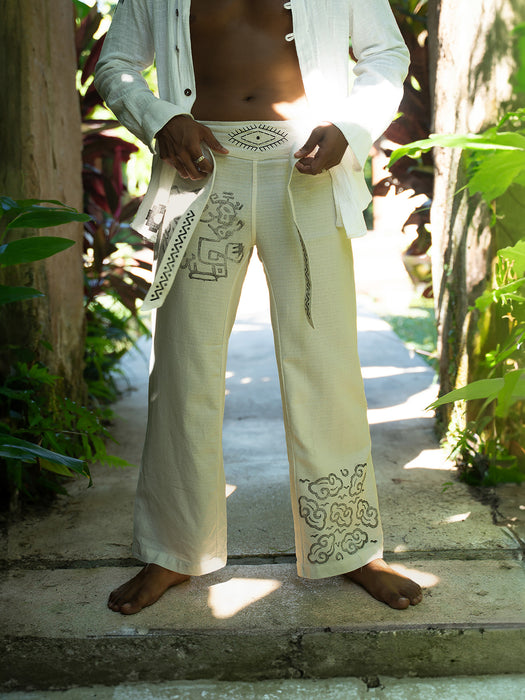Person wearing white embroidered pants and shirt in a tropical setting