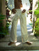 Person wearing white embroidered pants and shirt in a tropical setting