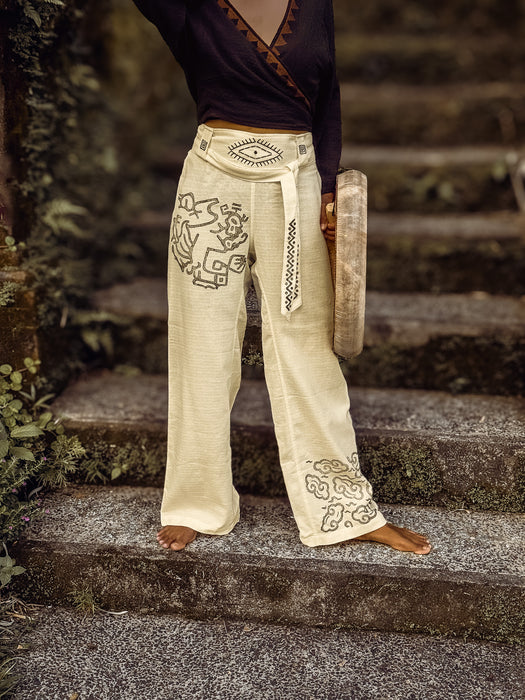 Person wearing embroidered beige pants standing on stone steps outdoors
