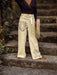 Person wearing embroidered beige pants standing on stone steps outdoors