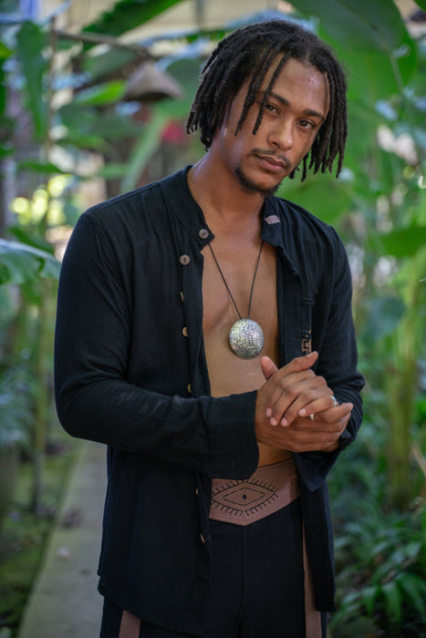 Man with dreadlocks wearing a black shirt in a tropical setting