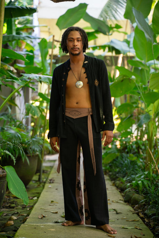 Man in traditional attire standing in a lush green garden