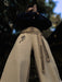 Person wearing beige pants with black patterns and designs, standing against a blurred natural background.