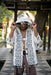 Person wearing a patterned white and black cardigan in an outdoor setting
