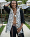 Man with dreadlocks wearing a patterned scarf in an outdoor setting with umbrellas.