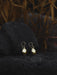 Hand-forged bronze earrings with tiny mirrors, displayed on an altar with feathers and herbs.