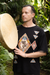 Man holding a large drum in a natural setting with greenery