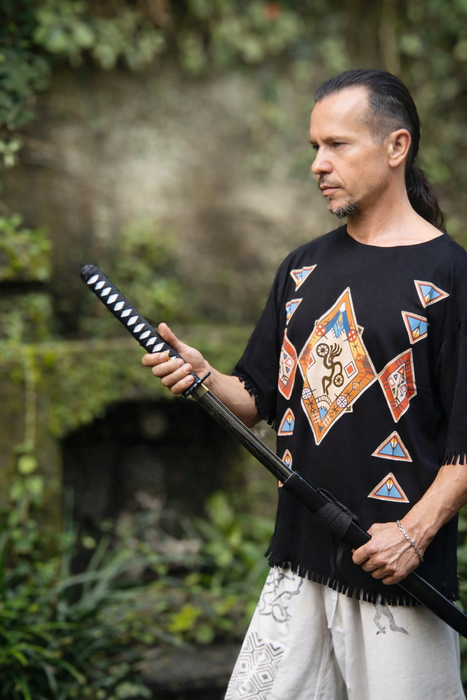 Man holding a sword outdoors with a blurred natural background