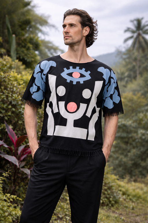 Man wearing a black sweater with abstract designs in a natural setting