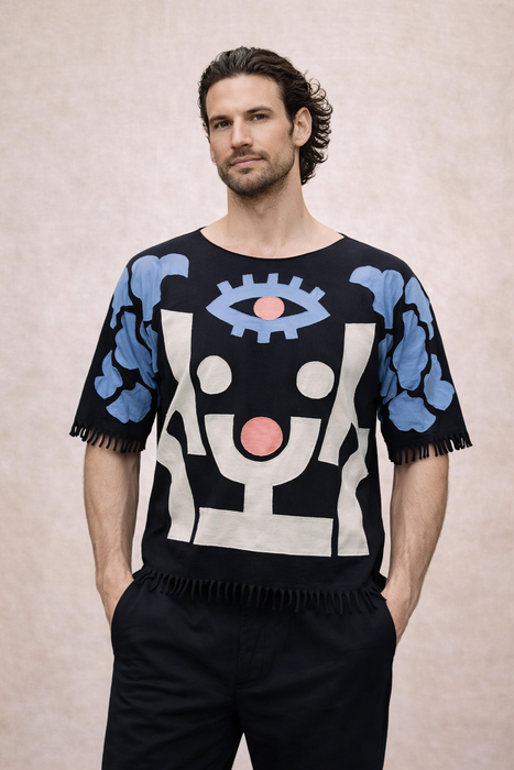 Man wearing a black sweater with abstract designs on a beige background
