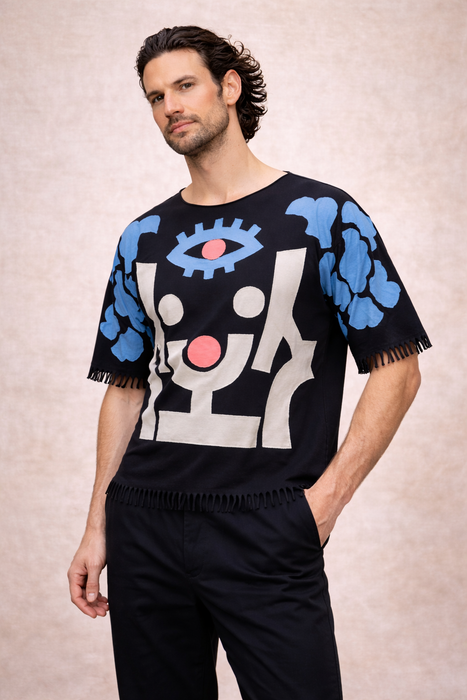 Man wearing a black t-shirt with abstract blue and white designs on a beige background