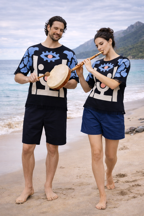 Two people on a beach playing musical instruments with mountains in the background