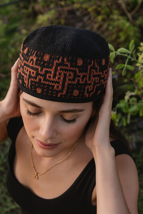 Woman wearing a black headscarf with orange patterns against a natural background