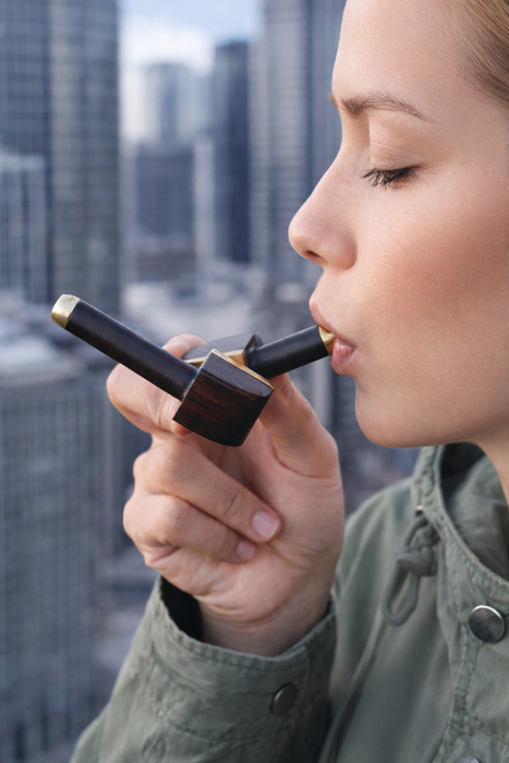 Woman using a lip gloss applicator with a cityscape in the background