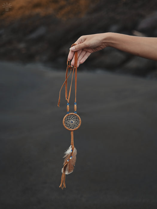 Tiny pastel-colored dream catcher amulet clipped to a baby’s crib, softly backlit by morning light