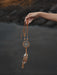 Tiny pastel-colored dream catcher amulet clipped to a baby’s crib, softly backlit by morning light