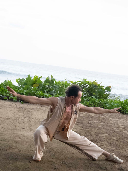 Person practicing martial arts on a dirt path with greenery in the background