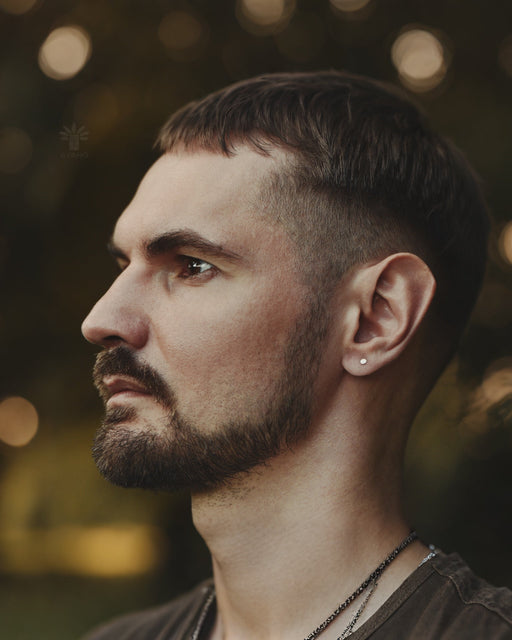 Close-up of model wearing minimalist flat disc earrings, highlighting their lightweight comfort and how they subtly catch light against bare skin