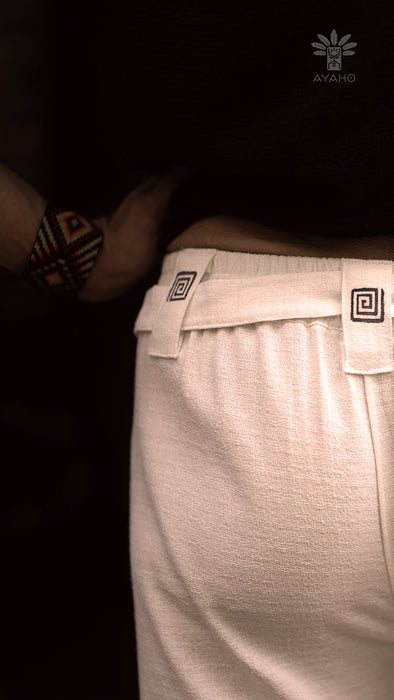 Close-up of a person wearing light gray pants with a dark background