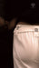 Close-up of a person wearing light gray pants with a dark background