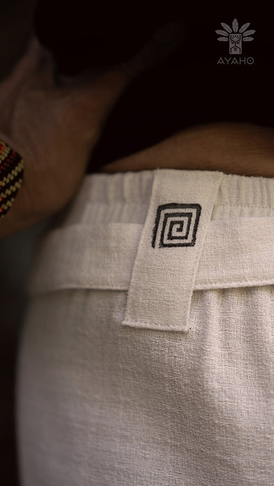 Close-up of a beige fabric with a black spiral pattern tag, worn by a person.