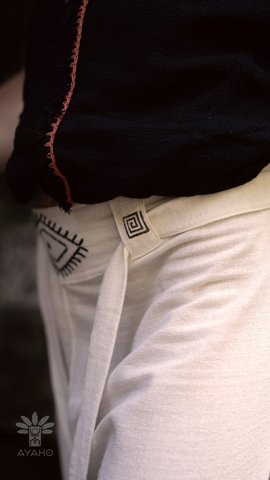Close-up of a person wearing white pants with a visible brand logo.