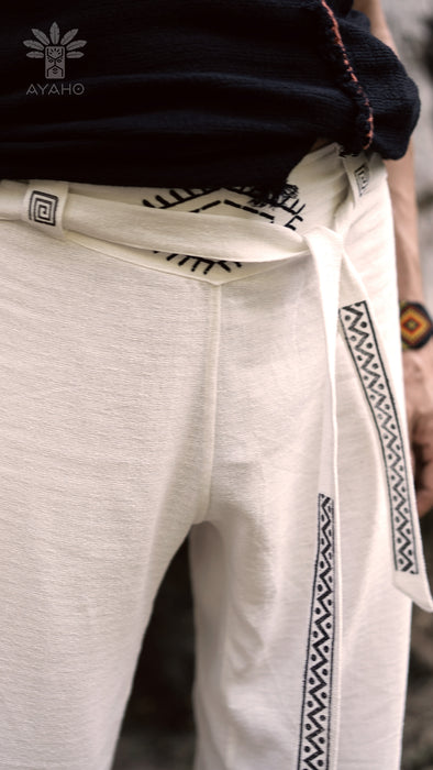 Close-up of light gray pants with black geometric patterns, worn by a person, with 'AYAHO' branding visible.