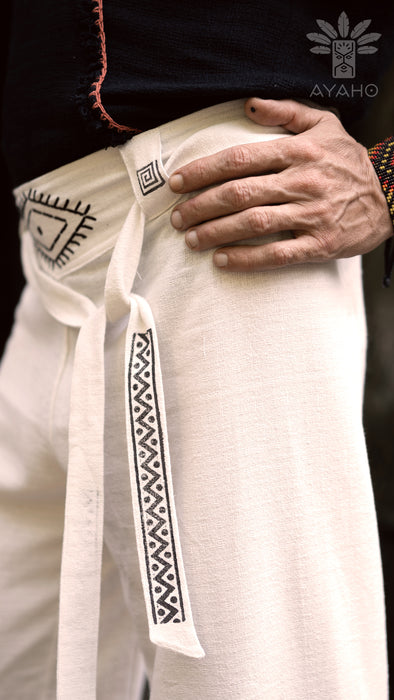 Close-up of a person wearing a white garment with black patterns, holding a white belt with black designs.
