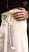 Close-up of a person wearing a white garment with black patterns, holding a white belt with black designs.