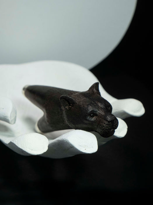 Black panther figurine on a white pedestal against a dark background