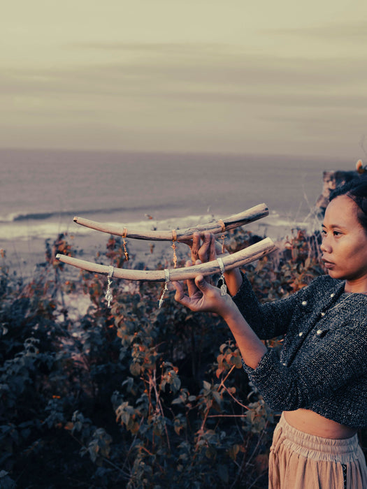 Person holding two large curved objects against a scenic background