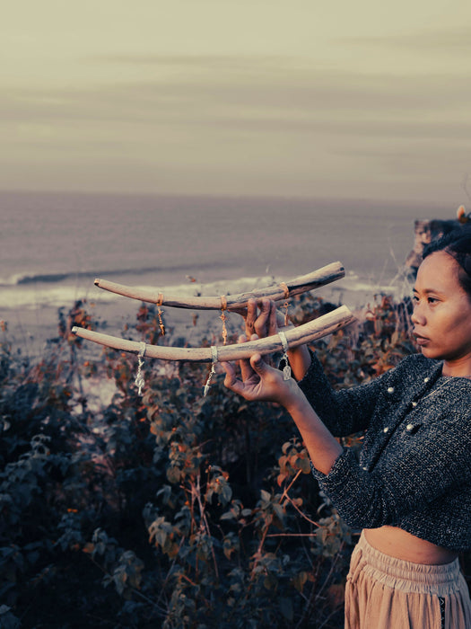 Person holding two large curved objects against a scenic background