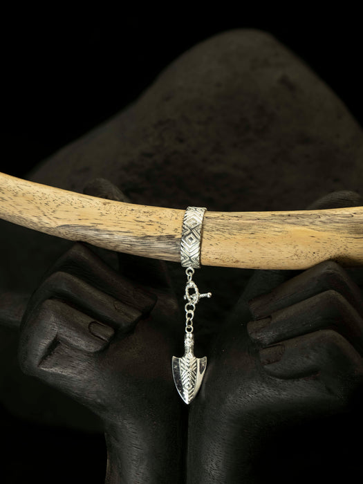 Silver bracelet with an arrowhead charm on a wooden stick against a dark background
