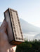 Wooden box with geometric pattern held by a hand against a mountainous background