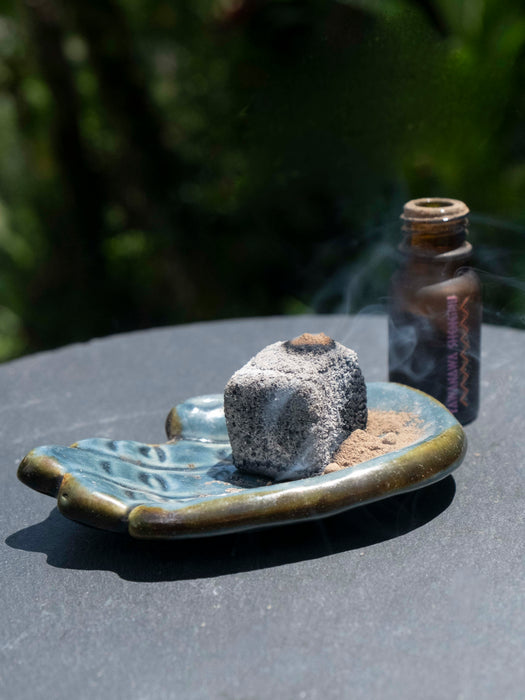 Ceramic dish with a rock and sand on a reflective surface