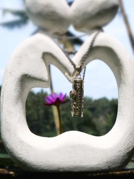 Necklace with a pendant hanging from a heart-shaped stone sculpture with a blurred natural background.