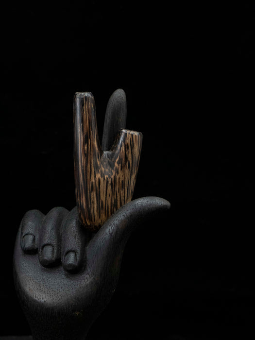 Decorative object shaped like a hand holding a stylized cigarette on a black background