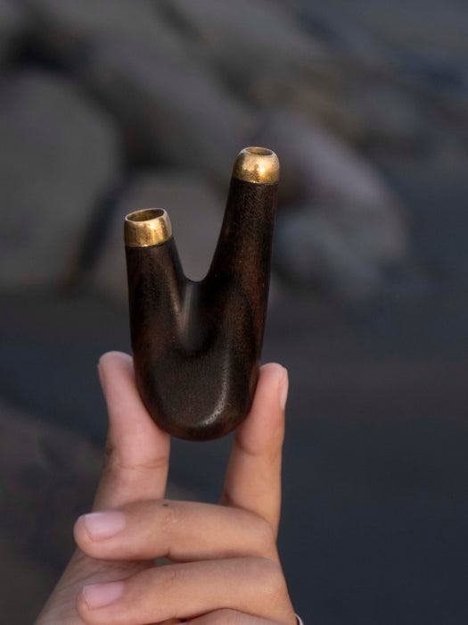 Wooden object with gold tips held by a hand against a dark background