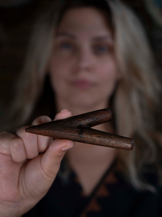 Person holding a wooden triangle instrument with a blurred background