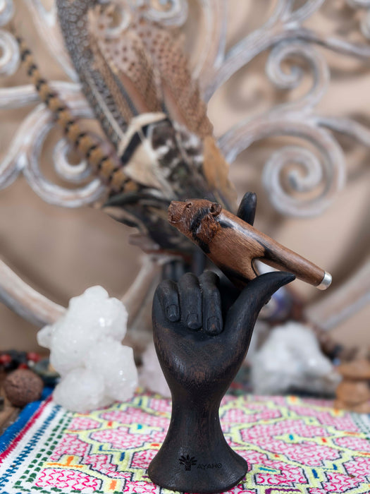Black hand sculpture holding a small brown bird against a decorative background