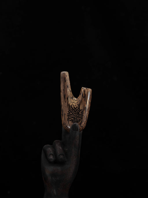 Hand holding a wooden tool against a black background