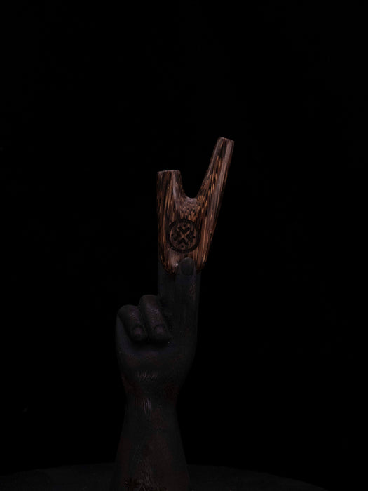 Wooden slingshot held by a hand against a black background