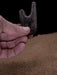 Hand holding a wooden boot jack on a brown surface with a black background