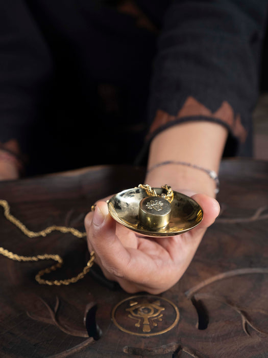 Hand holding a small gold object on a dark surface