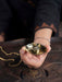 Hand holding a small gold object on a dark surface
