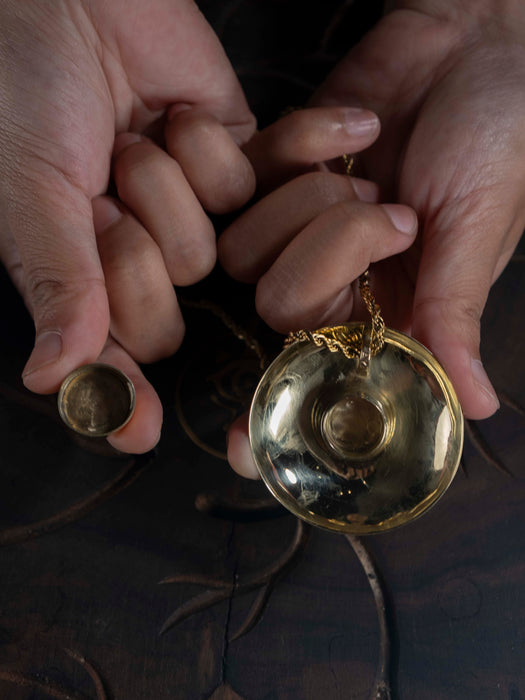 Gold pocket watch and case held by hands against a dark background