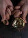 Gold pocket watch and case held by hands against a dark background